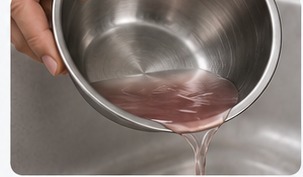 Auftauwasser wird aus einer Edelstahlschale abgegossen